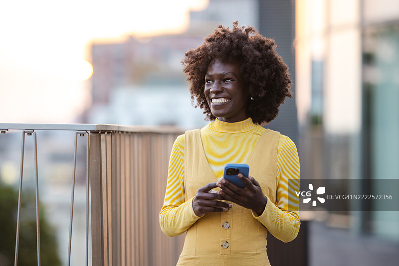 微笑的女性在阳光明媚的下午使用智能手机图片素材