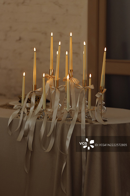 温暖餐厅内红色墙壁上的节日桌子上燃烧的蜡烛和丝带图片素材