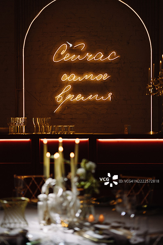 酒吧内部，砖墙上闪烁的霓虹灯标志，前景是烛光照亮的桌子图片素材