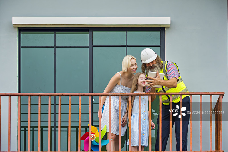 一名建筑工程师正在与一位母亲和女儿检查房屋质量。图片素材