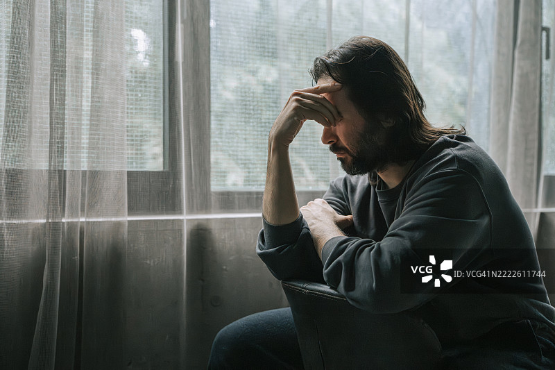 忧郁的男人坐在窗边沉思图片素材