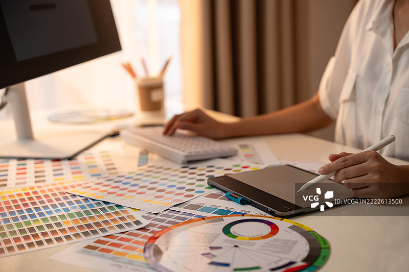 年轻的亚洲女性平面设计师在记录标志设计。色彩样本。艺术家在办公室的图形平板上绘制作品。平面设计师的创意编辑理念概念。图片素材