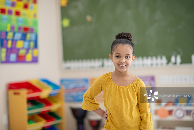 阳光明媚的教室里，充满色彩装饰的快乐小女孩图片素材