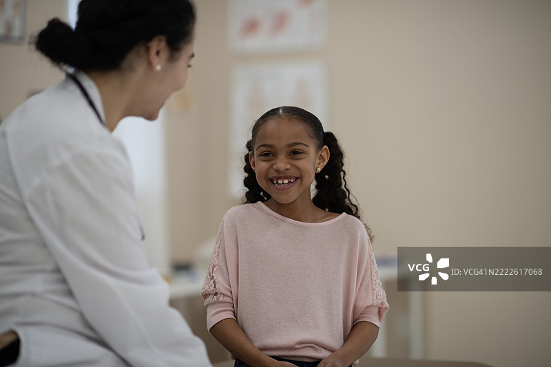 微笑的年轻女孩在友好的医疗环境中与儿科医生见面图片素材