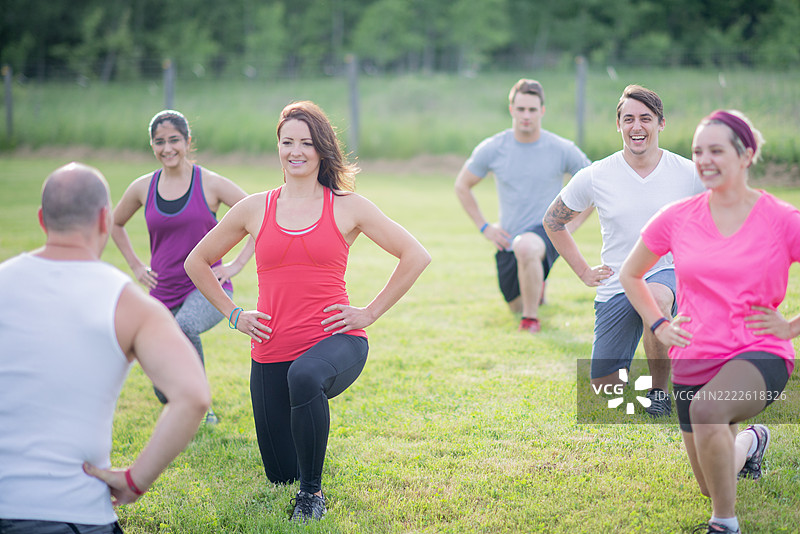 户外健身班在草地上进行弓步练习图片素材