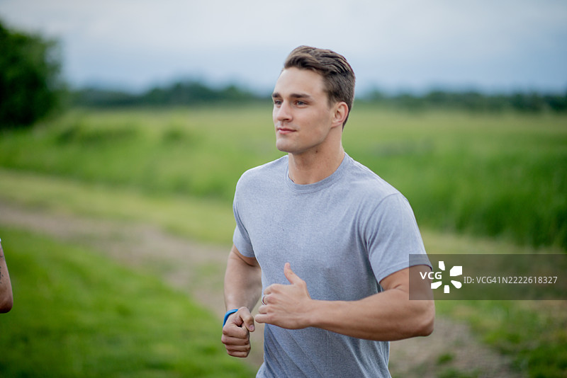 年轻男子在风景如画的自然小径上慢跑图片素材