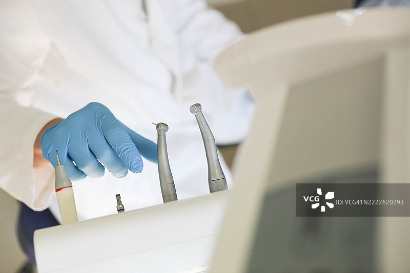 现代诊所中的牙科器械和戴手套的手图片素材