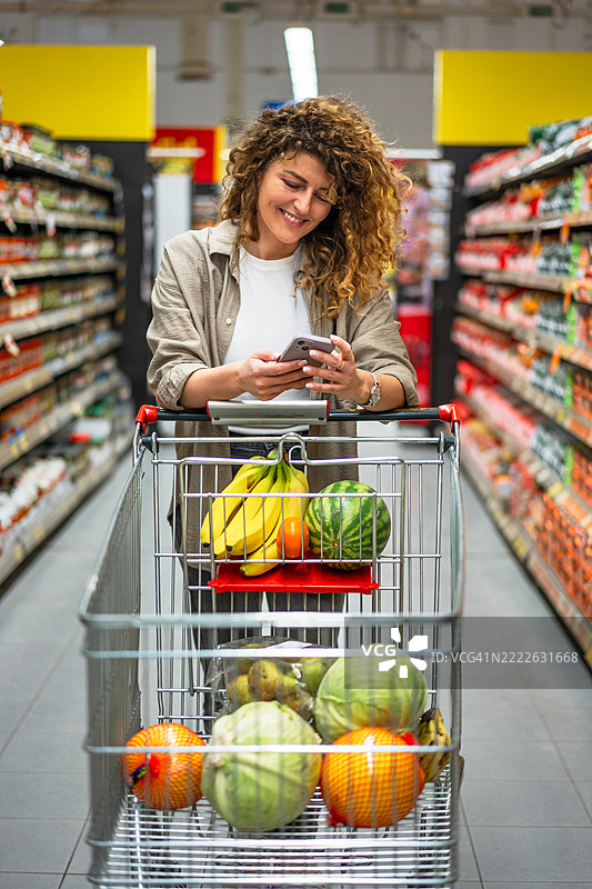 女性在超市购物时使用智能手机图片素材