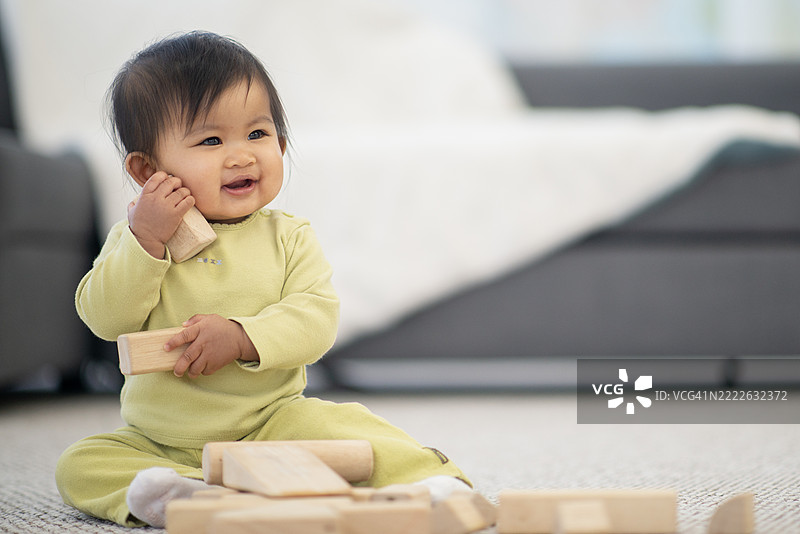 微笑的宝宝在温馨的家居环境中玩木块图片素材