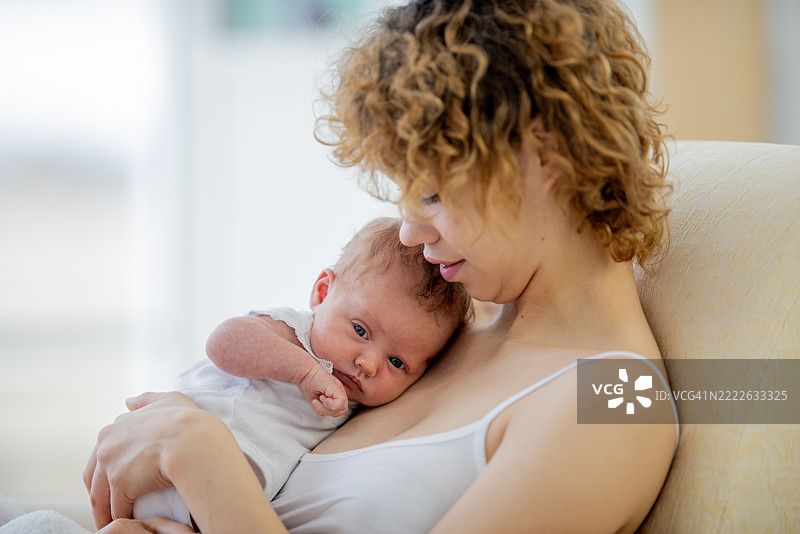 温柔的母亲在宁静的家中拥抱她的新生儿图片素材