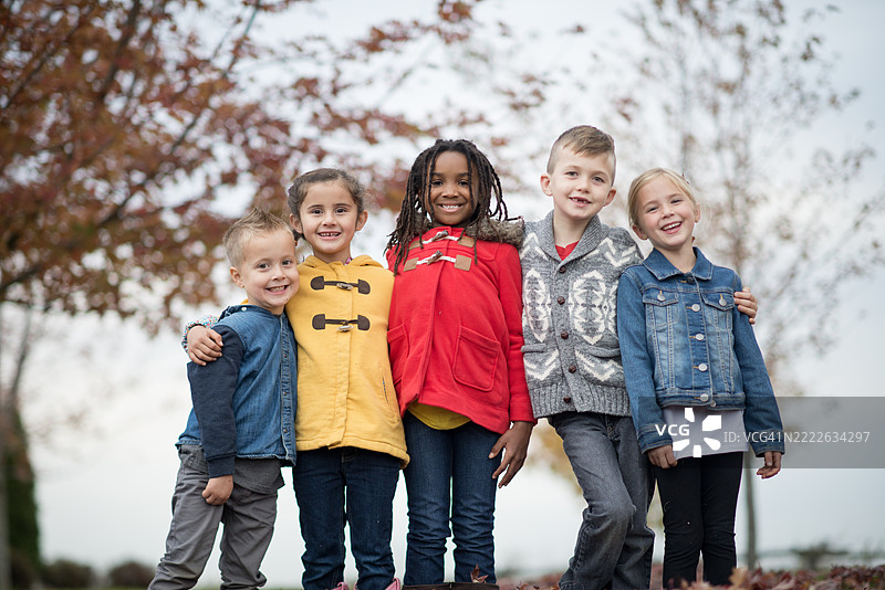 快乐的多元化孩子们在秋天的户外微笑图片素材