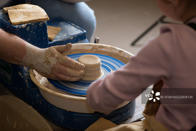 学生和老师的手在泥土中，陶艺轮上的陶杯图片素材
