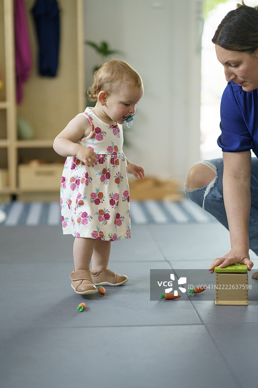 幼儿在室内玩玩具蔬菜，身边有父母陪伴图片素材