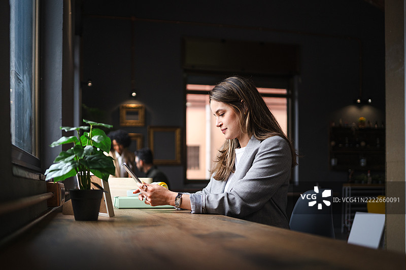 专业自由职业者在舒适的咖啡店里使用智能手机打字，享受无线网络和休闲工作环境的多任务处理。图片素材