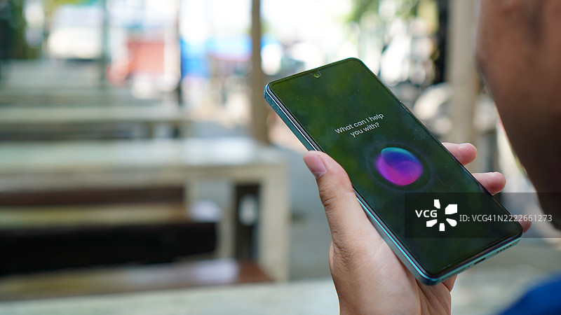 亚洲年轻男子在智能手机上使用语音助手图片素材