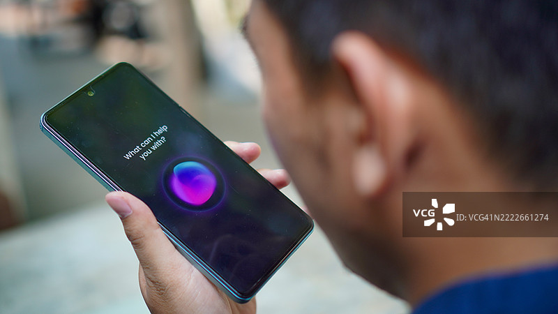 亚洲年轻男子在智能手机上使用语音助手图片素材