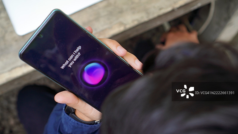 亚洲年轻男子在智能手机上使用语音助手图片素材