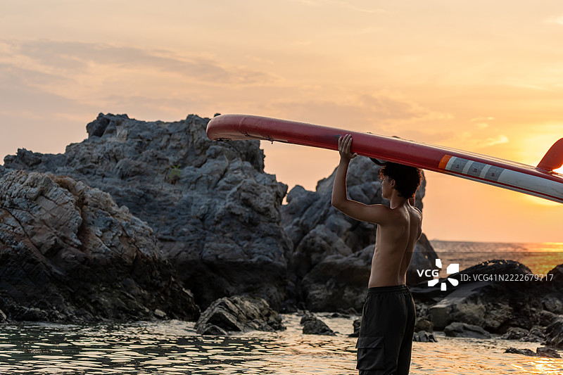 亚洲运动男士在海上划着冲浪板。泰国夏季假期的单人户外水上运动与旅行。图片素材