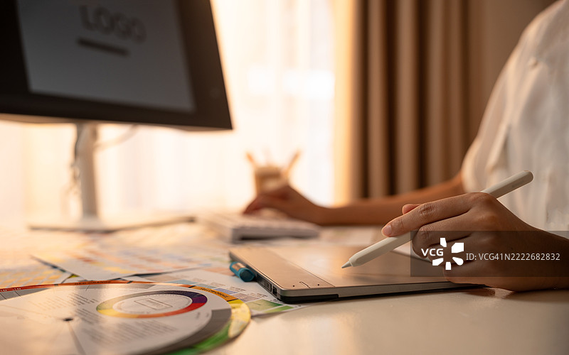 年轻的亚洲女性平面设计师在记录标志设计。色彩样本。艺术家在办公室的图形平板上绘制作品。平面设计师的创意编辑理念概念。图片素材