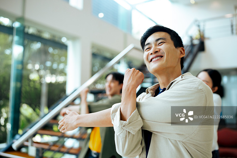 微笑的职业男性在办公室健康休息期间伸展身体图片素材