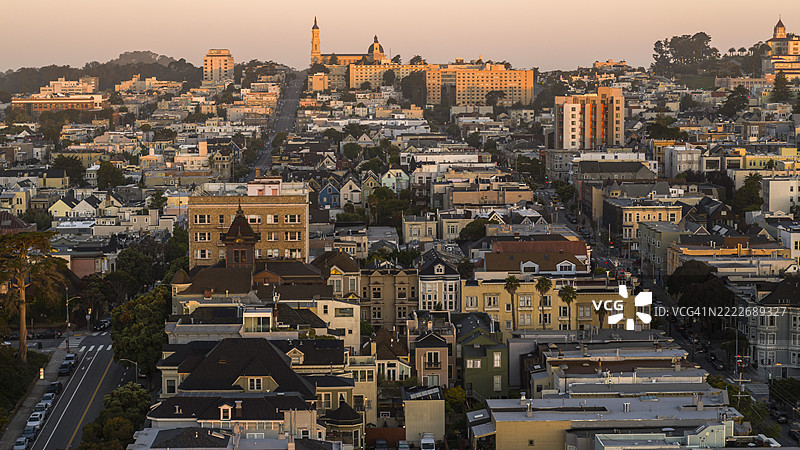 使命区的建筑沐浴在日出光辉中。维多利亚风格的住宅和教堂尖塔勾勒出加利福尼亚州旧金山的山丘。图片素材