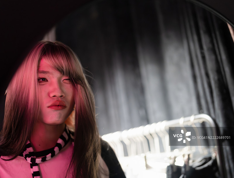 在黑暗的工作室里，年轻男子的特写，粉色灯光照耀。图片素材