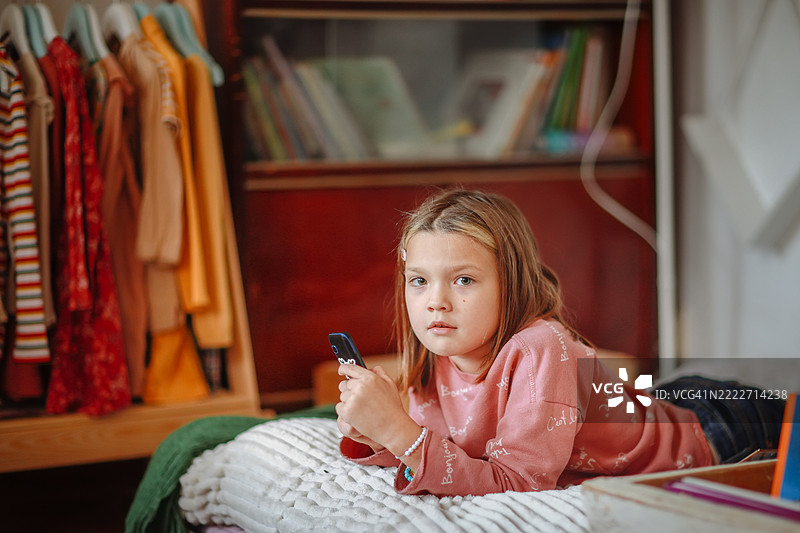 女孩在沙发上放松，手里拿着智能手机图片素材
