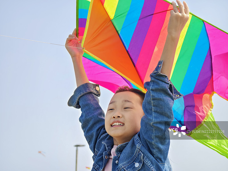 一个9岁的亚洲女孩在草原上放风筝，背景是明亮的天空和绿草。快乐的童年生活，教育。休闲。娱乐背景。图片素材