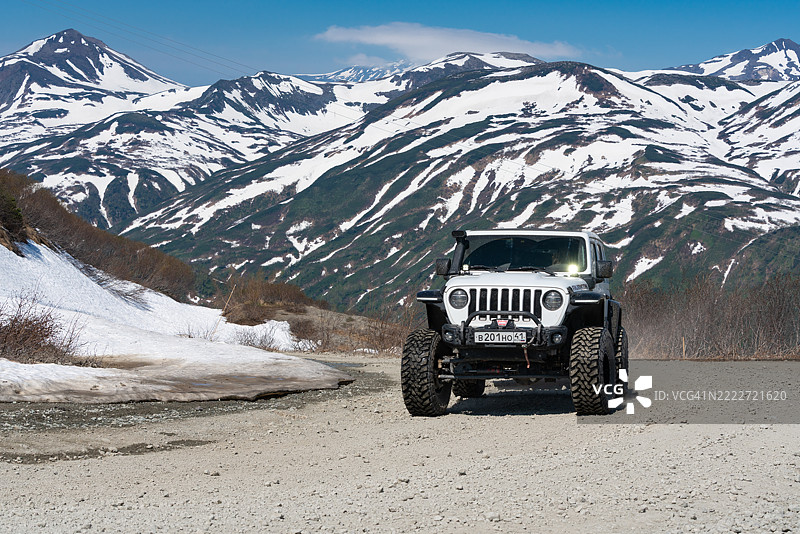 阳光明媚的日子里，吉普牧马人在山中的泥土路上行驶。图片素材