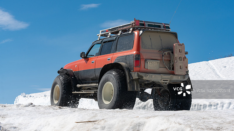 丰田兰德酷路泽在雪山的雪地道路上驾驶，配备超低气压轮胎。图片素材