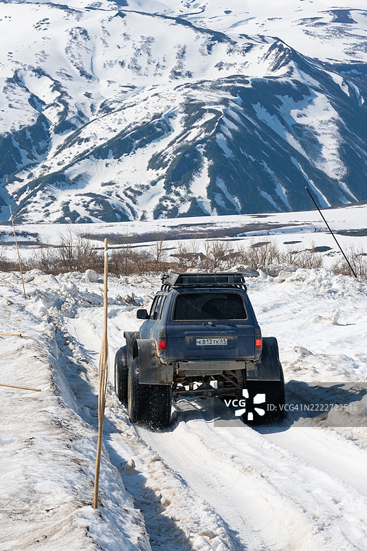 四轮驱动的丰田兰德酷路泽在阳光明媚的日子里，沿着被雪覆盖的山路行驶，轮胎气压极低。图片素材
