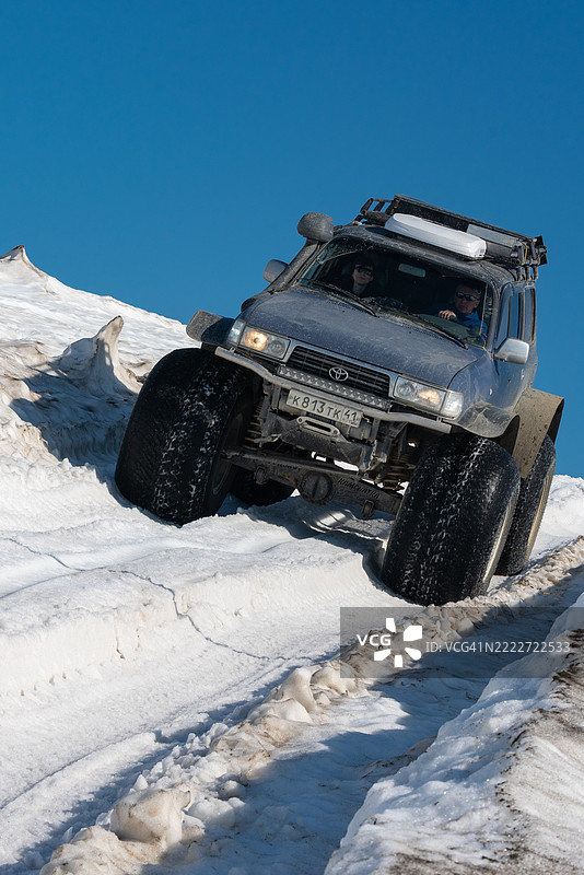 丰田陆地巡洋舰越野车在阳光明媚的日子里，驾驶着超低气压轮胎穿越雪覆盖的山地路线。图片素材