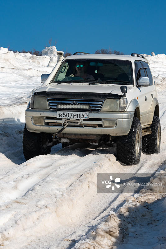 丰田兰德酷路泽普拉多正沿着阳光明媚的雪山公路行驶。图片素材