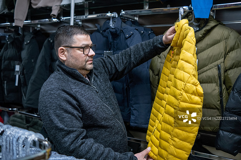 男人在挑选时尚的黄色羽绒服图片素材