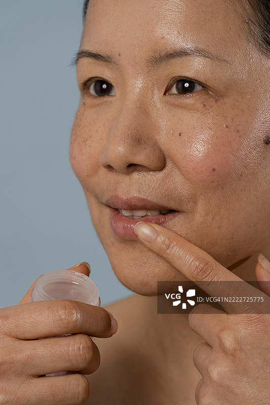 中年女性涂抹润唇膏图片素材