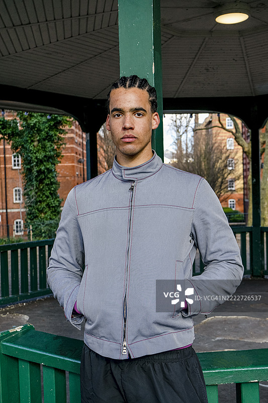 年轻男子在户外站立，双手插在口袋里图片素材