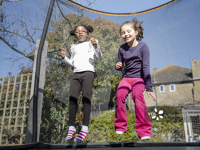 女孩们（6-7岁）在蹦床上跳跃图片素材