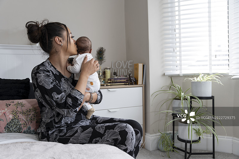 母亲在家中坐在床上抱着新生女婴图片素材