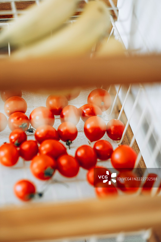 白色篮子里的小樱桃番茄，散落着，明亮的自然光，柔和的背景。厨房场景，新鲜农产品。图片素材