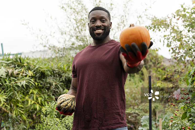 微笑的男子在城市花园里抱着南瓜的肖像图片素材