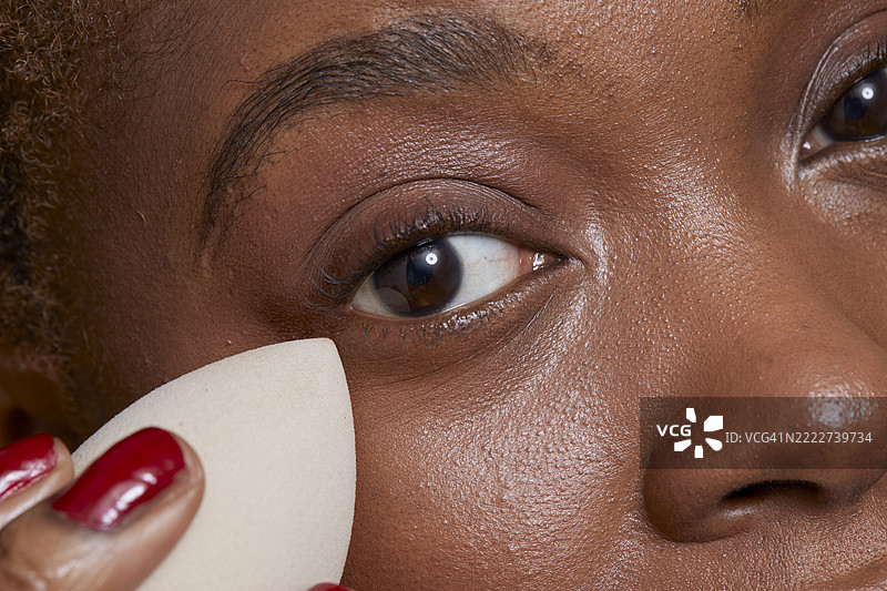 特写镜头：女性使用海绵涂抹化妆粉底。图片素材