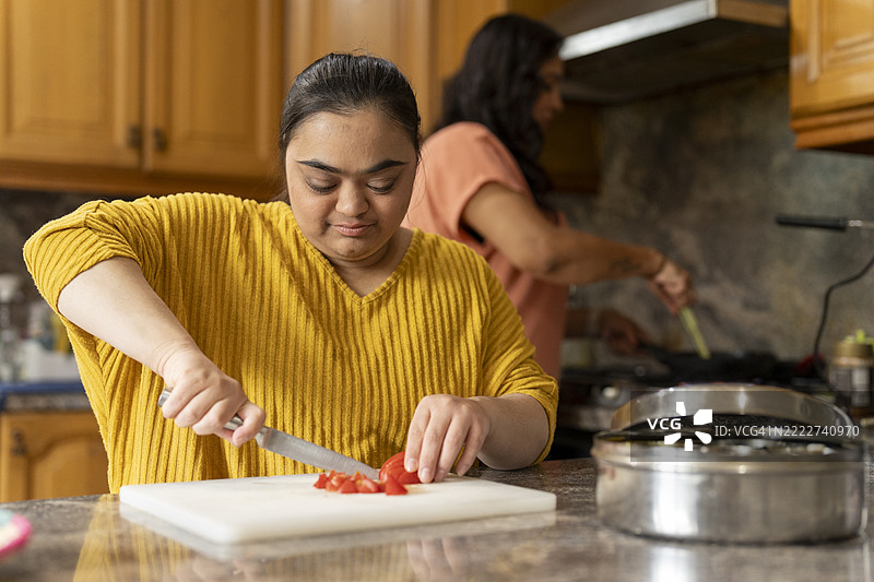 唐氏综合症女性与母亲在厨房准备食物图片素材