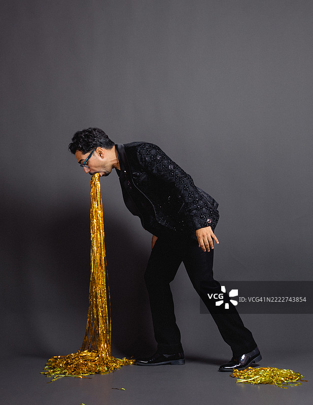 派对过载：男子幽默地呕吐金色彩带图片素材