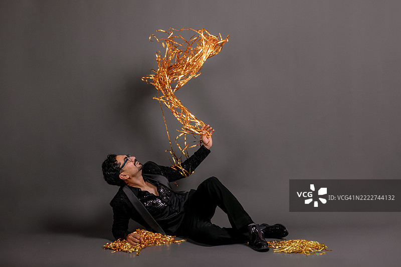 戏剧性的派对秋天 - 男子伸手去抓像电影场景般的五彩纸屑。图片素材