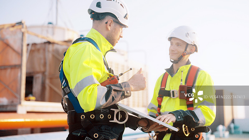 工人们正在检查建筑顶部的太阳能面板安装情况。图片素材