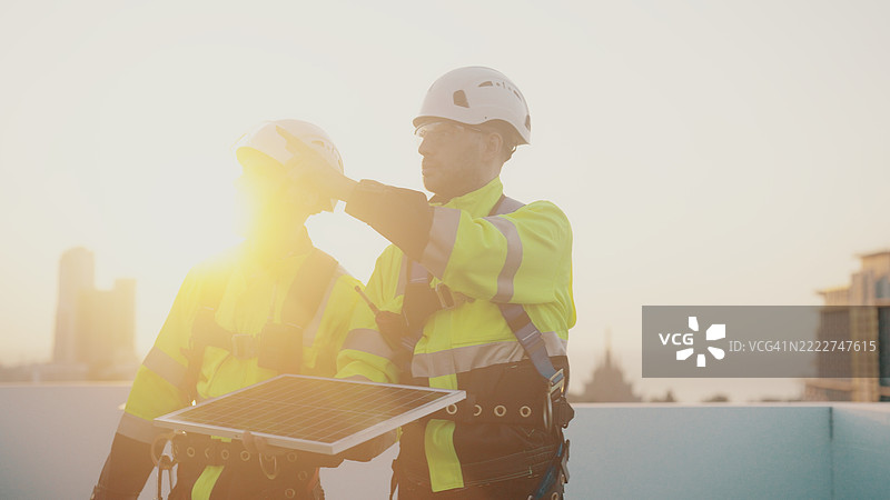 蓝领工人在检查建筑顶部的太阳能面板安装情况。图片素材