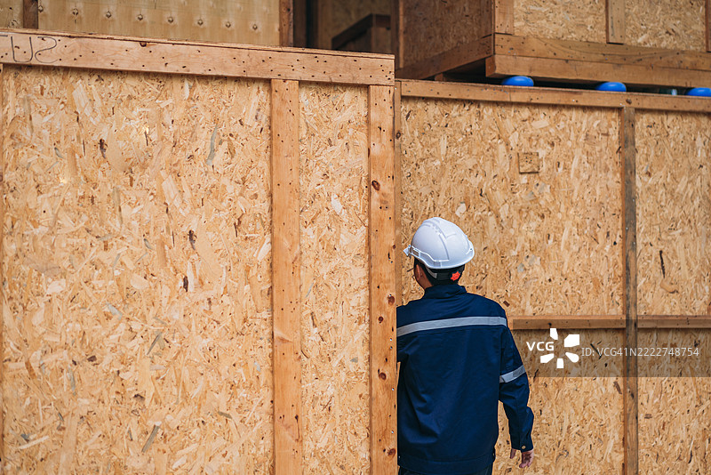 工程师们在宽敞的仓库内仔细检查装在大型木箱中的出口货物，确保质量和准备好进行国际运输。图片素材