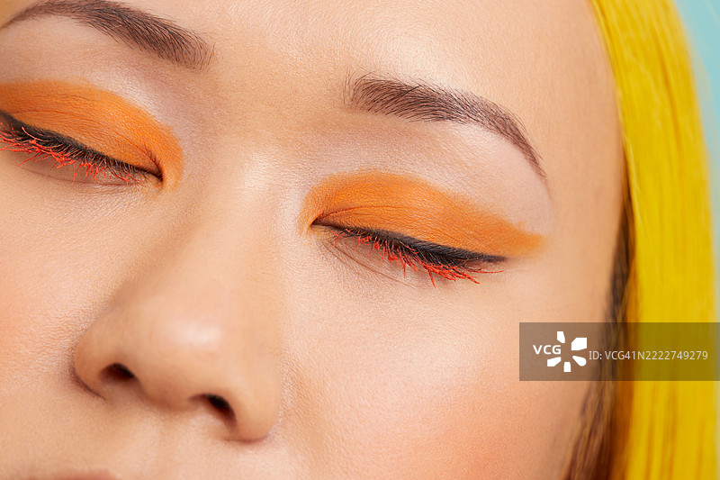 年轻女性，闭着眼睛，妆容为橙色图片素材