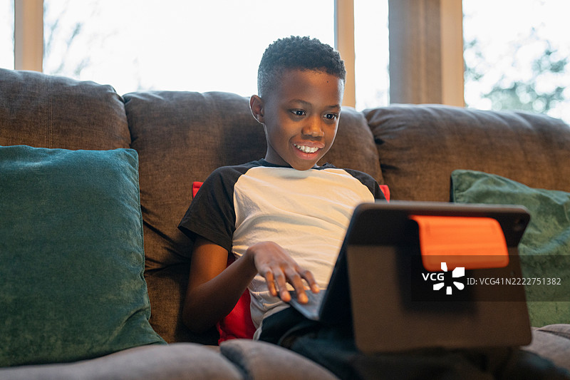坐在沙发上的男孩与笔记本电脑图片素材
