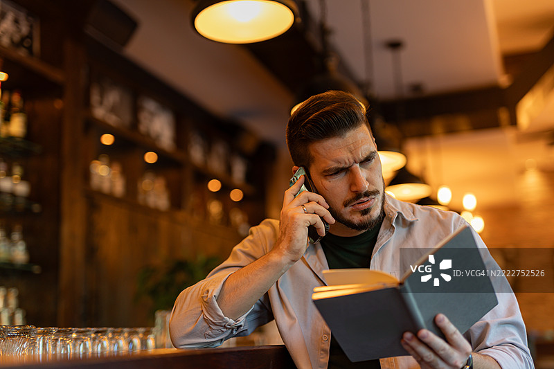 商人在酒吧里打电话并查看笔记图片素材
